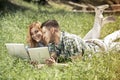 Young attractive couple lying on the grass, looking at laptop an Royalty Free Stock Photo