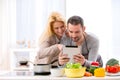 Young attractive couple reading recipe on a tablet