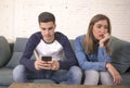 Young attractive couple in relationship problem with internet mobile phone addiction boyfriend ignoring sad neglected and bored gi Royalty Free Stock Photo