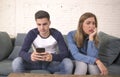 Young attractive couple in relationship problem with internet mobile phone addiction boyfriend ignoring sad neglected and worried Royalty Free Stock Photo