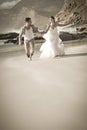 Young attractive couple running along beach wearing white Royalty Free Stock Photo