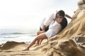 Young attractive couple sharing a kiss outdoors on beach rocks Royalty Free Stock Photo