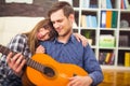 Young and attractive couple sitting near the couch with a guitar