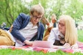 Young attractive couple wearing glasses is working or studying with laptop book note and pen lying on blanket in green Royalty Free Stock Photo