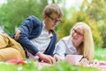 Young attractive couple wearing glasses is working or studying with laptop book note and pen lying on blanket in green Royalty Free Stock Photo