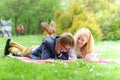 Young attractive couple wearing glasses is working or studying with laptop book note and pen lying on blanket in green park at sun Royalty Free Stock Photo