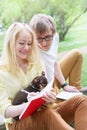 Young attractive couple wearing glasses is working or studying with laptop book note and pen sitting on blanket in green park at s Royalty Free Stock Photo