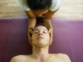 Young attractive and cute Asian woman giving traditional Thai massage to man lying on studio ground at tropical spa receiving Royalty Free Stock Photo