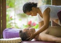 Young attractive and cute Asian woman giving traditional Thai massage to man lying on studio ground at tropical spa receiving Royalty Free Stock Photo