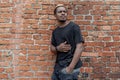 Young attractive dark-skinned man in black T-shirt on red bricked background. Royalty Free Stock Photo