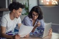 Young attractive diverse couple browsing internet, using laptop computer, smiling.