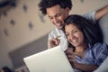 Young attractive diverse couple browsing internet, using laptop computer, smiling.