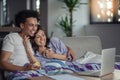 Young attractive diverse couple browsing internet, using laptop computer, smiling.