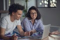 Young attractive diverse couple browsing internet, using laptop computer, smiling. Royalty Free Stock Photo