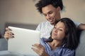 Young attractive diverse couple browsing internet, using laptop computer, smiling. Royalty Free Stock Photo