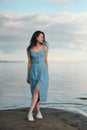 A young attractive dyed hair woman, in a blue dress, on background of seashore and sea. Royalty Free Stock Photo