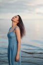 A young attractive dyed hair woman, in a blue dress, on background of seashore and sea. Royalty Free Stock Photo