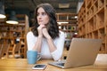 Young attractive elegant woman girl in casual clothes sitting at a table in a cafe with a laptop Royalty Free Stock Photo