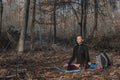 Young attractive european woman in sportswear doing yoga on the blue yoga mat in autumn forest. Woman making asana Royalty Free Stock Photo