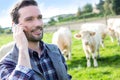 Young attractive farmer using mobile phone in a field