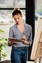 young attractive female artist using palette in front of easel Royalty Free Stock Photo