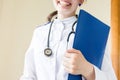 Young attractive female doctor in the office holding medical records and folders, she is smiling at camera Royalty Free Stock Photo