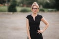 Young attractive female techer in black dress with sunglasses standing outside. Background of school Royalty Free Stock Photo