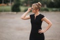 Young attractive female techer in black dress with sunglasses standing outside. Background of school Royalty Free Stock Photo