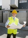 Young attractive foreman worker supervising building blueprints outdoors wearing construction helmet Royalty Free Stock Photo