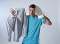 Young attractive and frustrated man holding iron and shirt stressed and tired in bored and lazy face