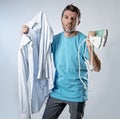 Young attractive and frustrated man holding iron and shirt stressed and tired in bored and lazy face