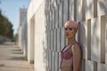 Young, attractive, gay man, heavily makeup, with pink hair and top, posing looking at the camera, relaxed and calm, leaning