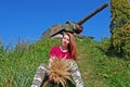 A young attractive girl with a bouquet of dry meadow grass is sitting on the grass under the slide on which ISU-152 stands. Royalty Free Stock Photo