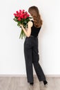 Young attractive girl with a bouquet of red rosesin full growth on a white background, back view.  The concept of happiness, joy Royalty Free Stock Photo