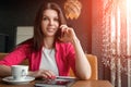 Young attractive girl, businesswoman, talking on mobile phone sitting alone in coffee shop . Happy female having rest in cafe. Royalty Free Stock Photo