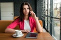 Young attractive girl, businesswoman, talking on mobile phone sitting alone in coffee shop . Happy female having rest in cafe. Royalty Free Stock Photo