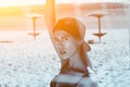 Young attractive girl in a cap and a bathing suit standing near the volleyball net on the beach