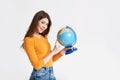 A young attractive girl chooses a place to rest on a large globe. Vacation, travel. Portrait on a light background Royalty Free Stock Photo