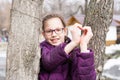Young attractive girl in glasses makes a heart shape with palms in a city park in early spring Royalty Free Stock Photo