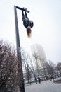 Young attractive Girl hanging by feet upside down on the street light in the street. super extreem. concept of courage