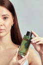 Young attractive girl with long brown hair holds a bottle of face wash. Caucasian woman caring for the skin to maintain Royalty Free Stock Photo