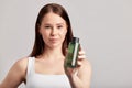 Young attractive girl with long brown hair holds a bottle of face wash. Caucasian woman caring for the skin to maintain Royalty Free Stock Photo