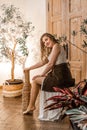 A young attractive girl with long flowing blond hair is sitting on a chair