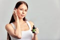 Young attractive girl with long hair applying healing serum on her face. Caucasian woman caring for the skin to maintain Royalty Free Stock Photo