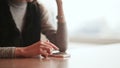 Young attractive girl with a phone in hands is sitting at a table in a cafe. Break for rest. Close-up of a girl`s hand.