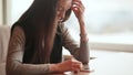 A young attractive girl with a phone in her hands sits at a table in a cafe. Break for rest.