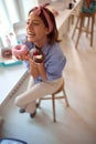 A young attractive girl in a pastry shop is in love with delicious donuts she holds in hands. Pastry shop, dessert, sweet