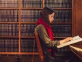 Young attractive girl reading a book in the library Royalty Free Stock Photo