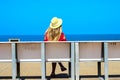 Young attractive girl in a red dress sitting on a bench near the sea in the summer, Batumi, Georgia Royalty Free Stock Photo