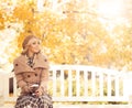 Young and attractive girl sitting on a bench in an autumn park Royalty Free Stock Photo